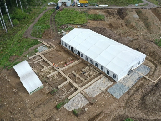Grabung von oben, rechts das Zelt, link die  2023 ausgegrabenen Schichten und Mauern, zwei Archäologen inmitten der Mauern