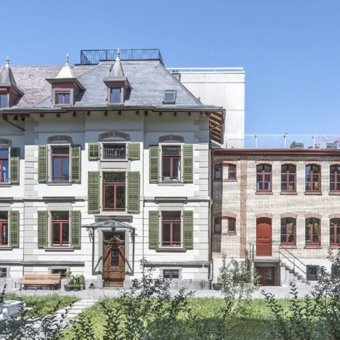 Fassadenansicht mit Haustüre und Fenstern mit dem Garten im Vordergrund