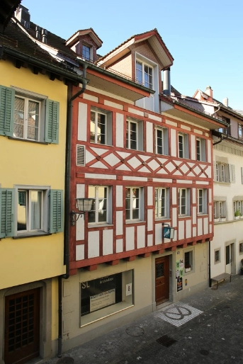 Frontfassade mit roten Hölzern und weissem Putz der Taube