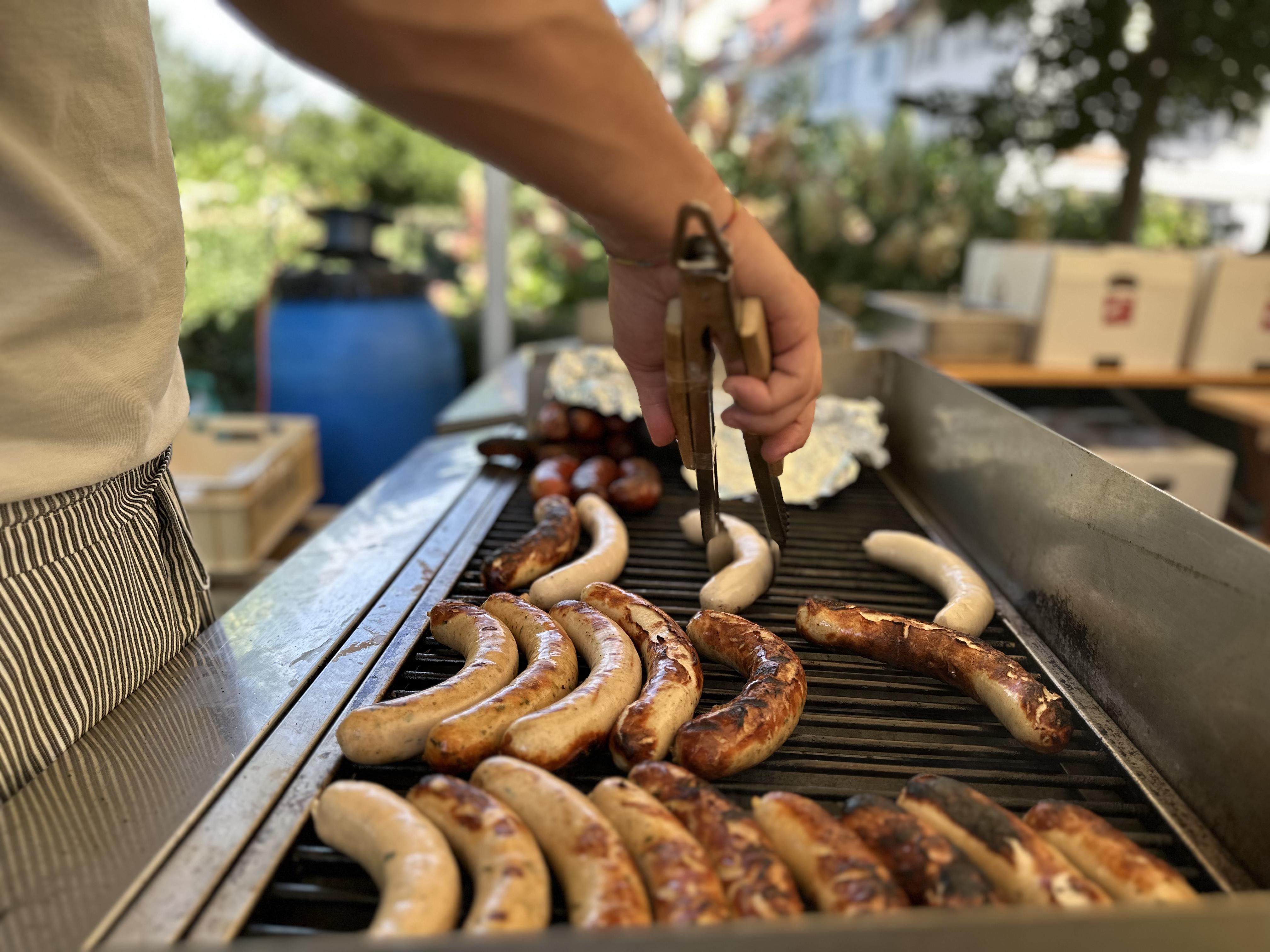 Auf dem Grill liegen diverse Wurstspezialitäten, auch vegetarische, für die hungrigen Gäste bereit.
